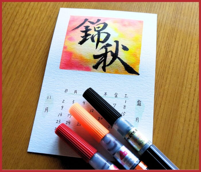 錦秋の筆文字と赤・黄色のにじみがある11月カレンダー作品と筆ペン